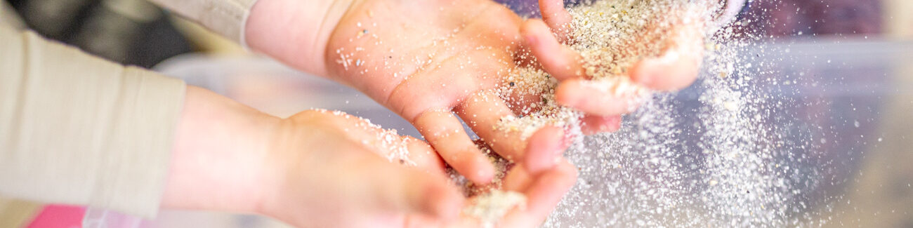 Impressionen aus der Kita. Spielende Kinder, Kinderhände spielen mit Sand.